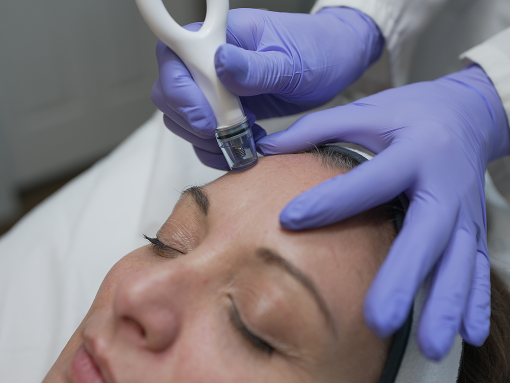 A patient closes her eyes while a cosmetic specialist adminsters the DiamondGlow treatment