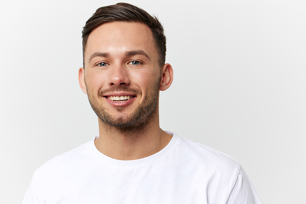 A young man with smooth skin smiles